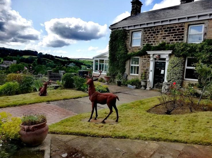 A stone farmhouse framed by clipped topiary and mixed border planting