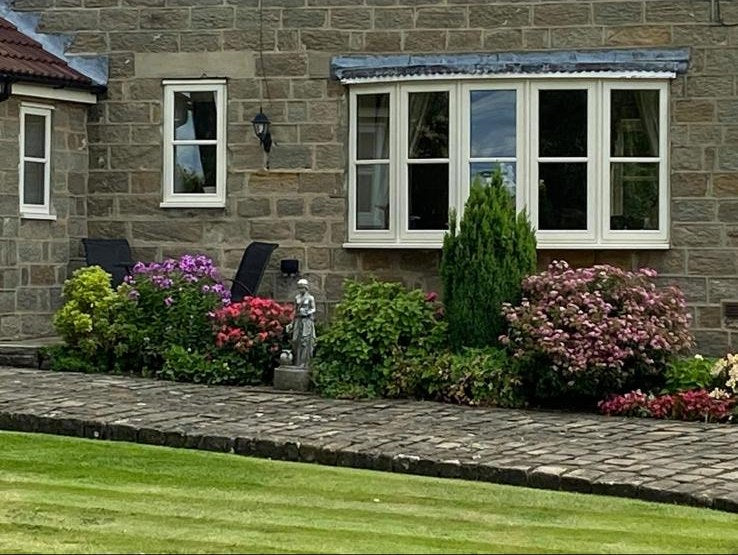 Hydrangeas, azalea and shrubs planted under the windows of a stone house