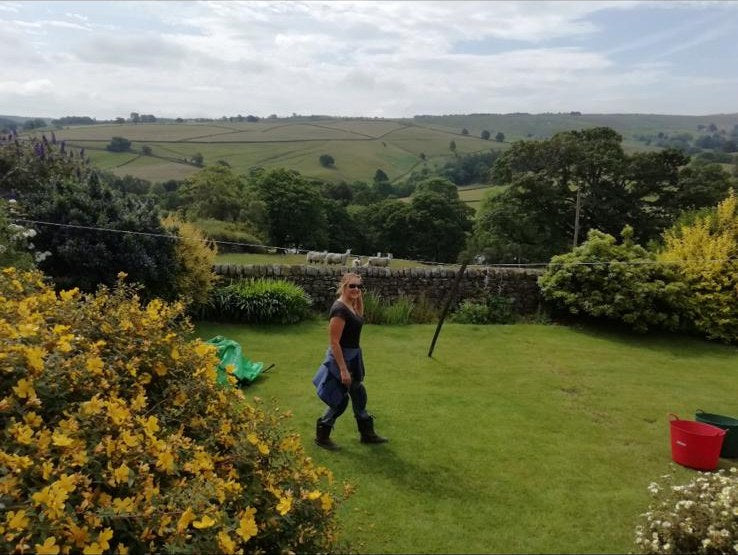 Karen heading across the lawn on a maintenance visit, fields and sheep behind