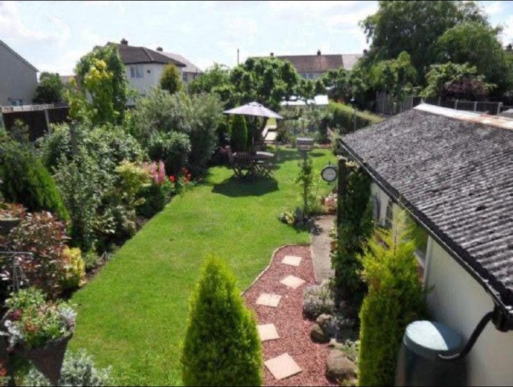 A long back garden kept up, lawn, borders, gravel path and seating