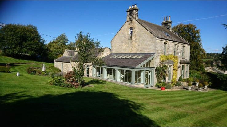 Lawn cut and striped on a regular visit at a stone house with a garden room