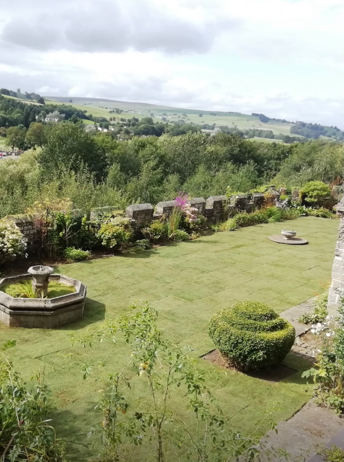 A newly turfed lawn running down to a stone wall and a dales view