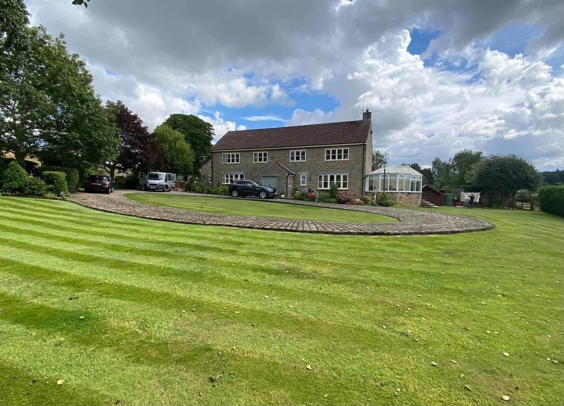 A freshly striped lawn sweeping up to a stone farmhouse