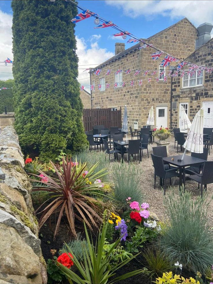 A planted terrace bed at a village pub, bunting up and tables out