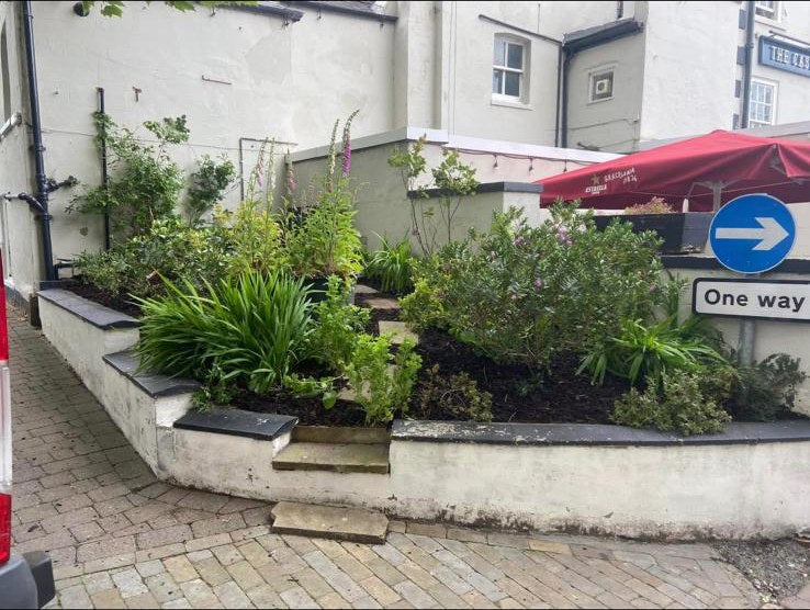 Rendered raised planters filled with agapanthus and shrubs outside a village pub